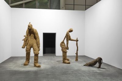 Large sculptures of two men with guns, along with a third of a stretching dog. One of the men is missing his body, with a stick acting as the spine for his back.