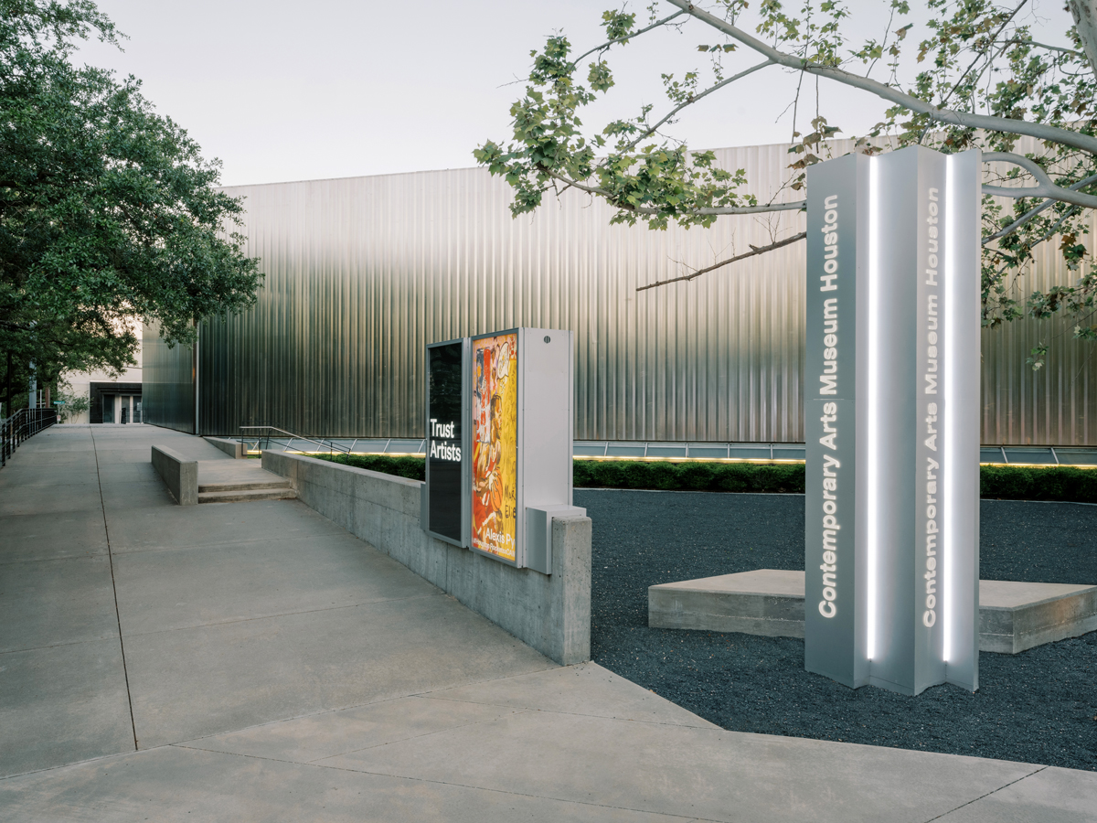 Exterior view of a building that looks like corrugated stainless steel. At front is a plinth that reads 'Contemporary Arts Museum Houston'