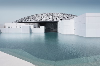 A silver dome is surrounded by white buildings and blue water.