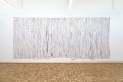 A wide, unevenly shaped painting composed of white bra straps.