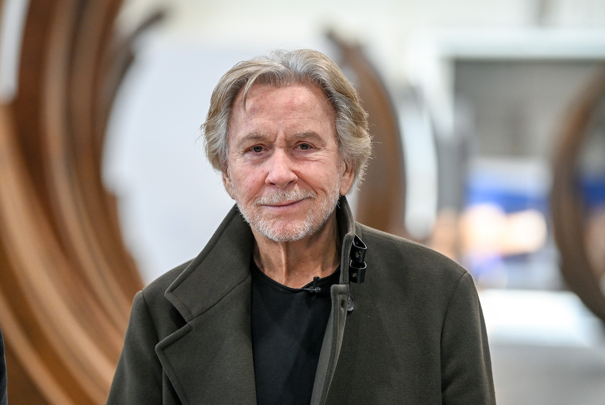 A smiling white man in a grey coat.