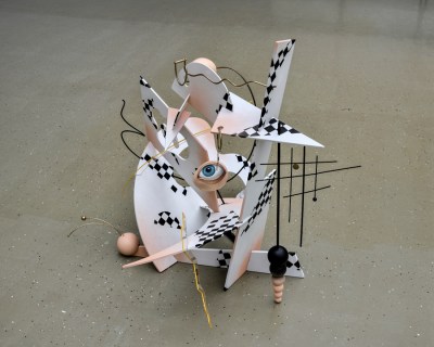 A sculpture on a floor resembling partially checkerboarded planes that intersect. At its center, there is an eyeball.