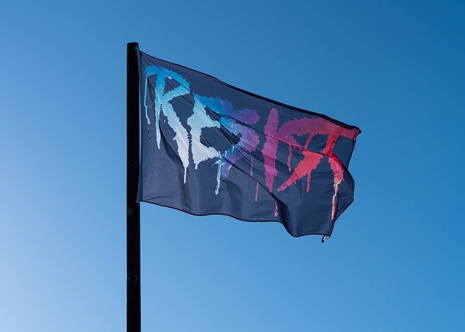 Black flag with the word RESIST in multicolored lettering.