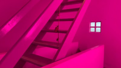 A magenta-lit staircase with bells tied to a string that runs through its stairs.