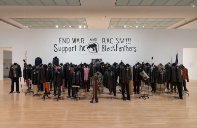 A group of headless mannequins beneath a sign that reads 'END WAR AND RACISM!!! Support the Black Panthers.'